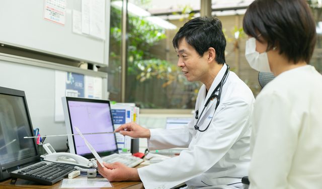 画面を指しながら患者さんに説明する院長