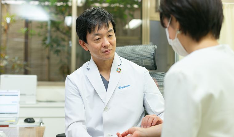 院長が患者さんの手に触れながら診察している様子