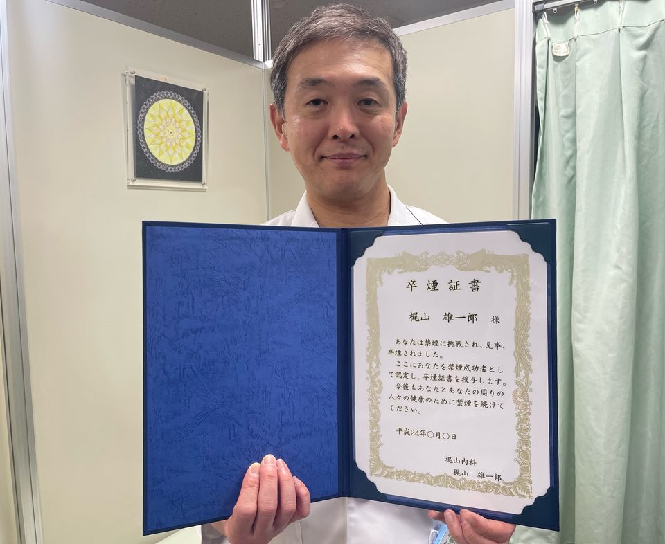 卒煙証書を開いて持つ院長