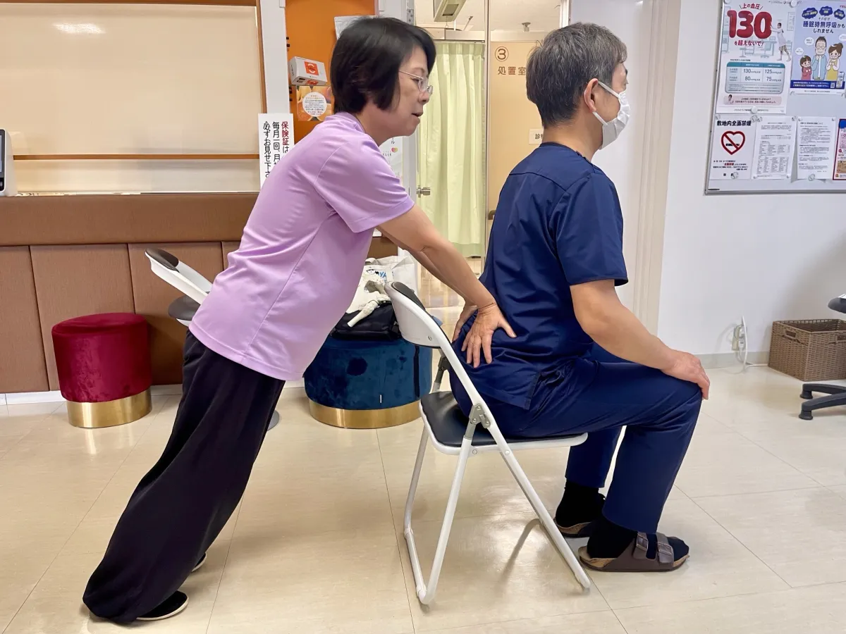 10月22日の教室の様子。講師が、椅子に座った院長の背中に手を添えて、姿勢を確かめている